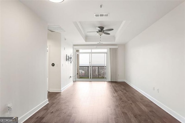 unfurnished room featuring ceiling fan, dark hardwood / wood-style floors, and a raised ceiling