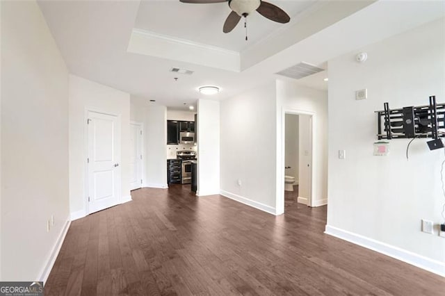 unfurnished living room with a tray ceiling, dark wood-type flooring, ornamental molding, and ceiling fan