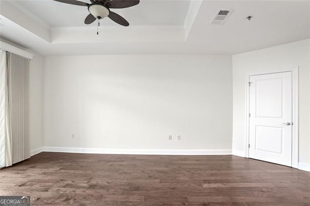 unfurnished room with crown molding, a tray ceiling, dark wood-type flooring, and ceiling fan