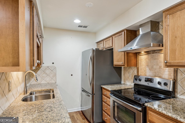 kitchen featuring wall chimney exhaust hood, sink, tasteful backsplash, appliances with stainless steel finishes, and light stone countertops