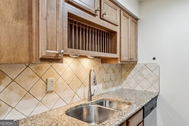 kitchen featuring tasteful backsplash, light stone countertops, sink, and stainless steel dishwasher