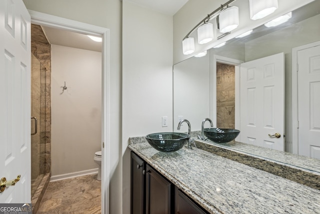 bathroom featuring a shower with door, vanity, and toilet