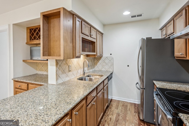 kitchen featuring tasteful backsplash, sink, stainless steel dishwasher, light stone counters, and light hardwood / wood-style floors