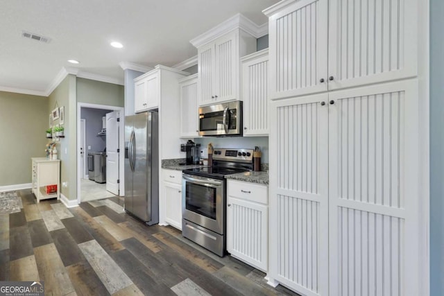 kitchen with white cabinetry, ornamental molding, dark stone counters, and appliances with stainless steel finishes