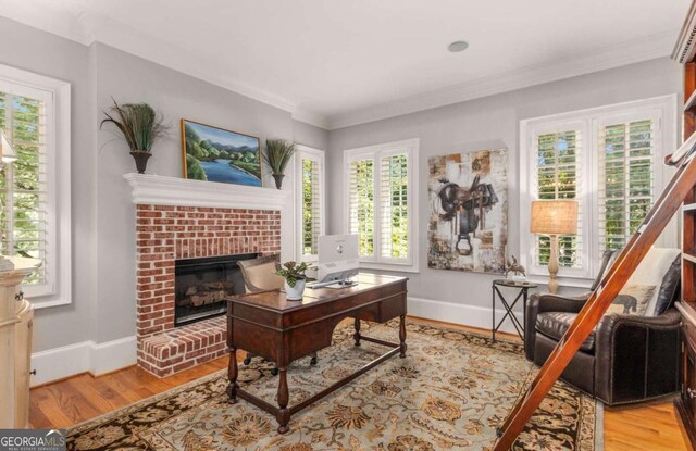 office area featuring a brick fireplace, crown molding, and light hardwood / wood-style floors