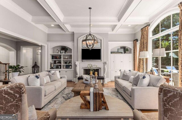 living room featuring coffered ceiling, a chandelier, light hardwood / wood-style flooring, built in features, and beam ceiling