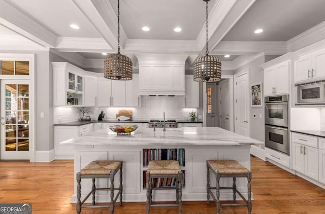 kitchen featuring stainless steel appliances, a kitchen island with sink, pendant lighting, and a breakfast bar