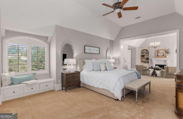 carpeted bedroom with ceiling fan with notable chandelier and vaulted ceiling