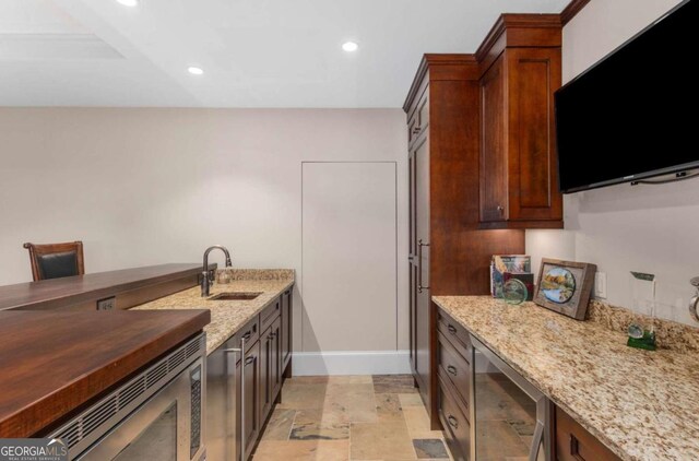 kitchen featuring wine cooler, sink, stainless steel microwave, and dark stone counters