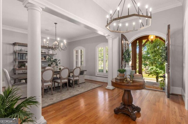 interior space featuring an inviting chandelier, ornamental molding, light hardwood / wood-style floors, and decorative columns