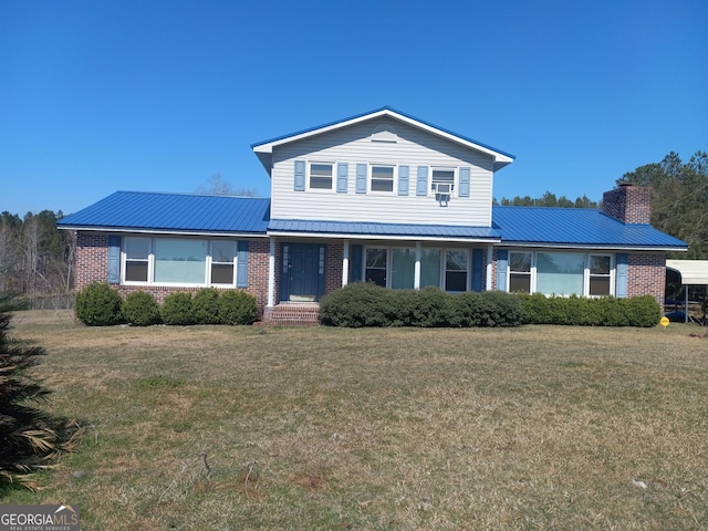 traditional home with metal roof, a chimney, a front lawn, and brick siding