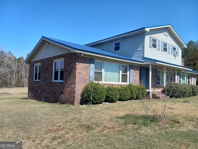 traditional-style house with metal roof, brick siding, and a front lawn