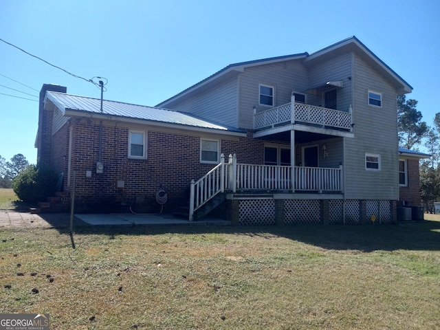 back of property with a patio, a balcony, metal roof, a yard, and brick siding