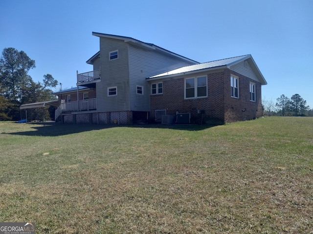 view of home's exterior with a balcony, metal roof, crawl space, a yard, and brick siding