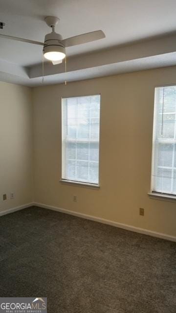 empty room with ceiling fan and dark colored carpet