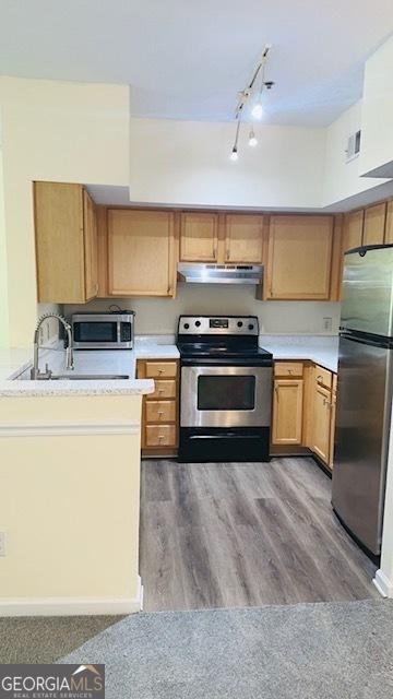 kitchen with rail lighting, appliances with stainless steel finishes, and light hardwood / wood-style floors