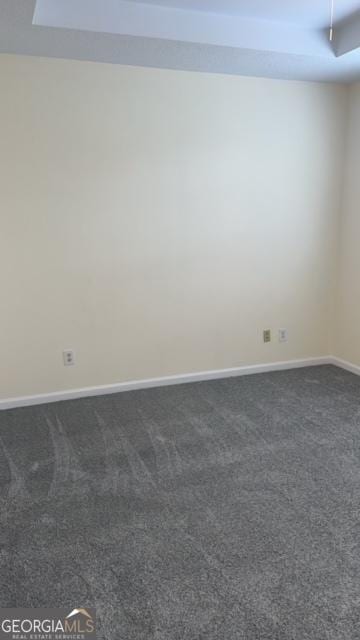 spare room featuring dark colored carpet