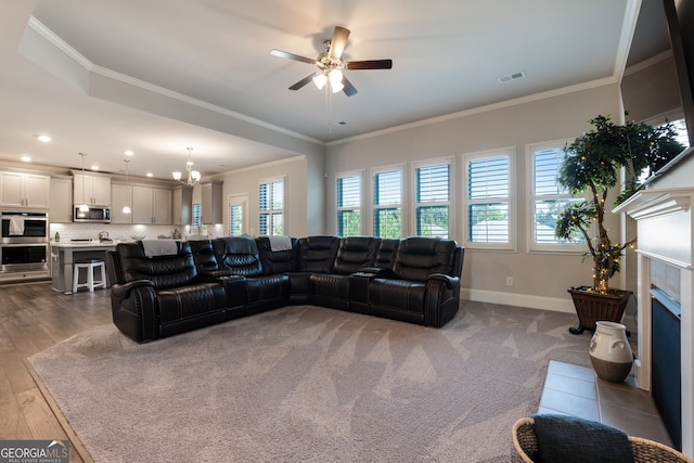 living room featuring ornamental molding, a fireplace, ceiling fan with notable chandelier, and light hardwood / wood-style flooring