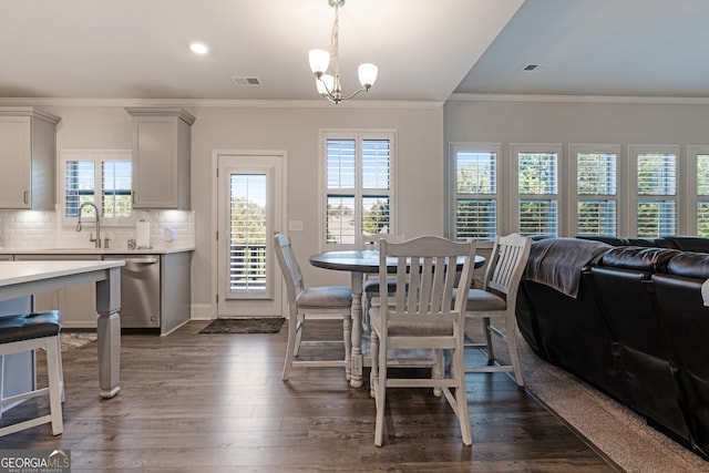 dining area featuring ornamental molding, dark hardwood / wood-style flooring, sink, and a notable chandelier