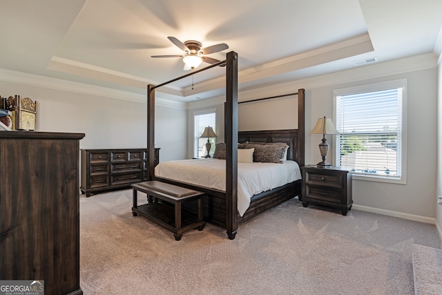 carpeted bedroom with ornamental molding and a tray ceiling