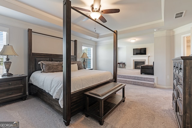 bedroom with light carpet, crown molding, a raised ceiling, and ceiling fan