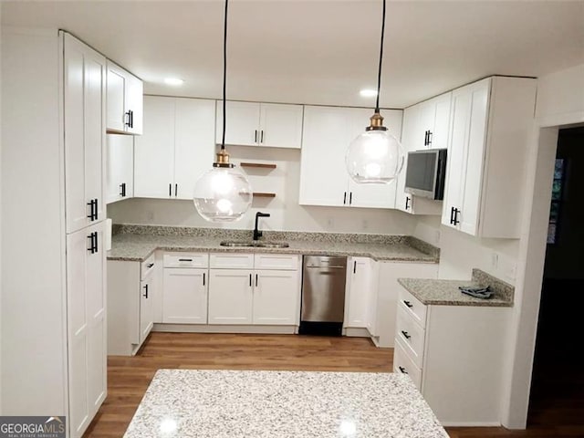 kitchen featuring sink, white cabinetry, decorative light fixtures, light hardwood / wood-style flooring, and dishwasher