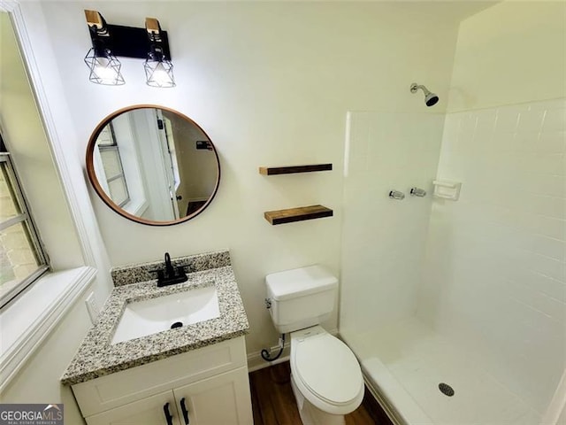 bathroom featuring vanity, hardwood / wood-style floors, a shower, and toilet