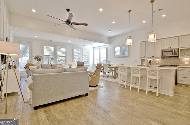 living room featuring ceiling fan, a healthy amount of sunlight, and light wood-type flooring