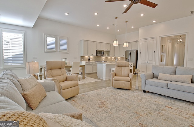 living room with ceiling fan, sink, and light hardwood / wood-style floors