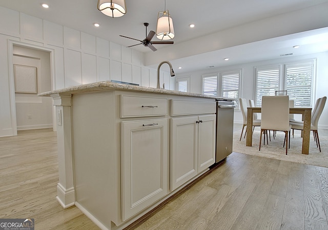 kitchen featuring hanging light fixtures, sink, light hardwood / wood-style floors, and an island with sink