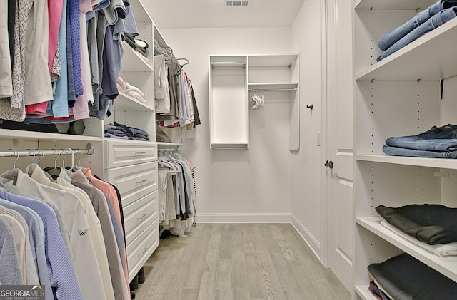 walk in closet with light hardwood / wood-style floors