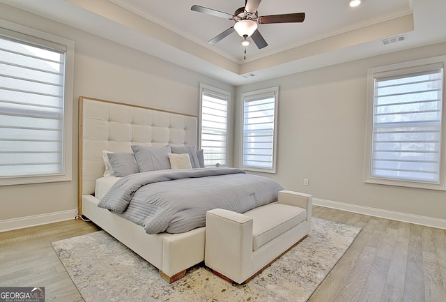 bedroom with hardwood / wood-style flooring, ornamental molding, and a raised ceiling