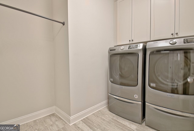 washroom featuring cabinets and washer and clothes dryer