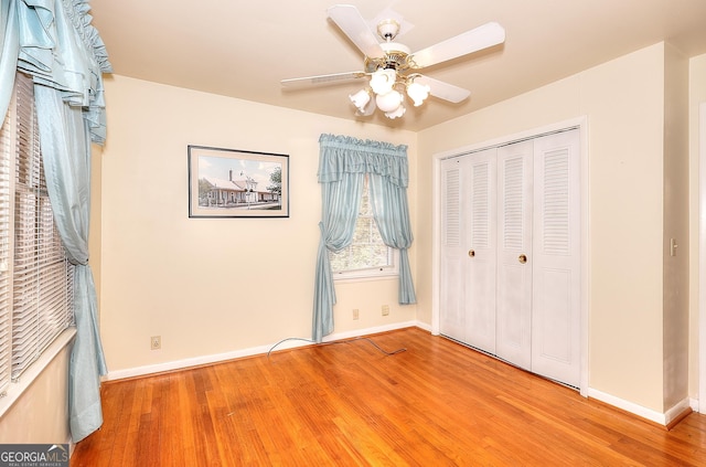 unfurnished bedroom featuring hardwood / wood-style floors, a closet, and ceiling fan