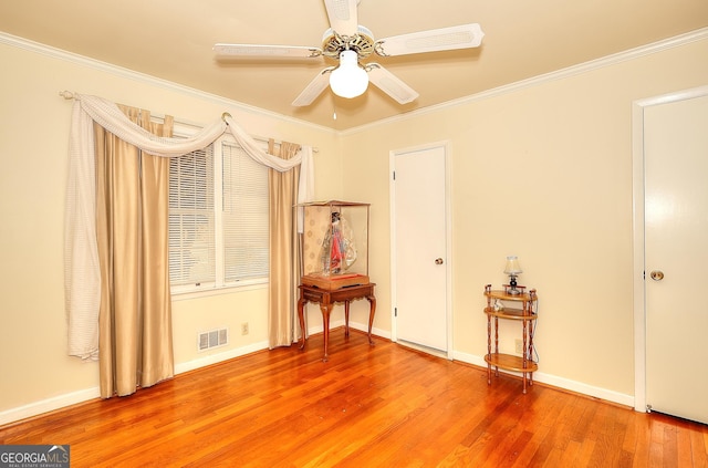 empty room with crown molding, ceiling fan, and hardwood / wood-style floors