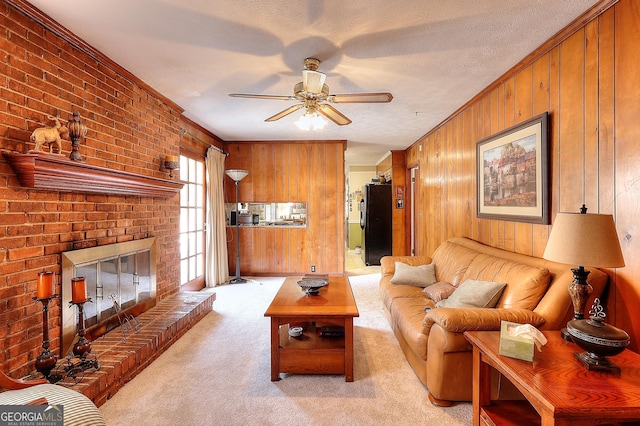 carpeted living room with crown molding, a fireplace, ceiling fan, and wood walls