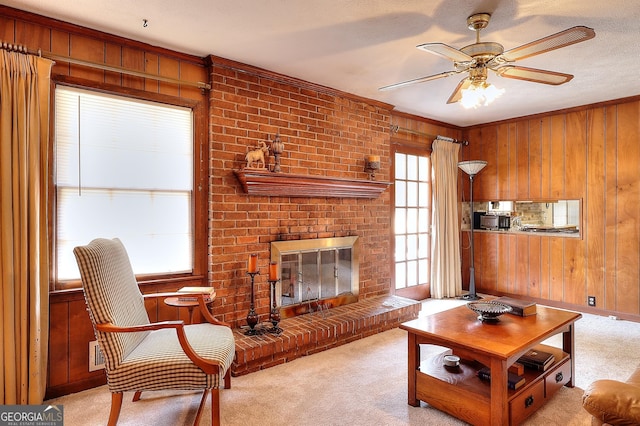 living room featuring ceiling fan, a brick fireplace, light carpet, and wooden walls