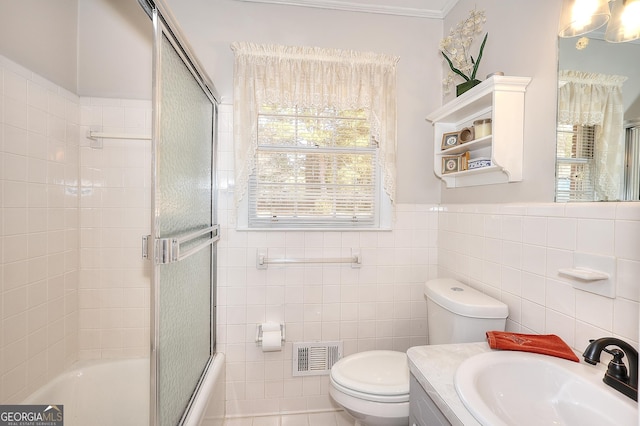 full bathroom with shower / bath combination with glass door, vanity, toilet, and tile walls