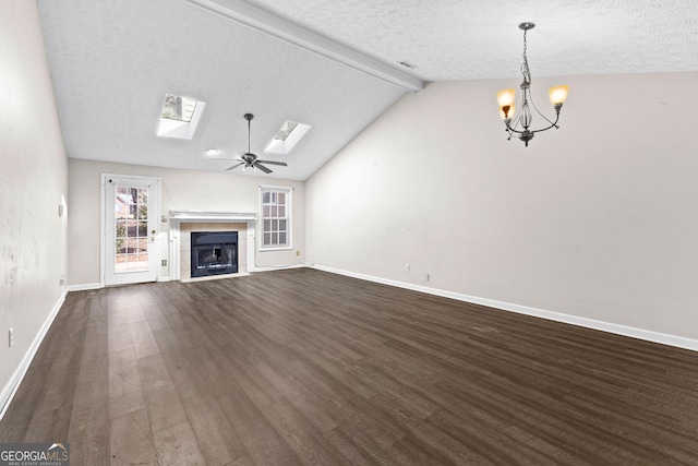 unfurnished living room with dark hardwood / wood-style floors, vaulted ceiling with skylight, a fireplace, a textured ceiling, and ceiling fan with notable chandelier