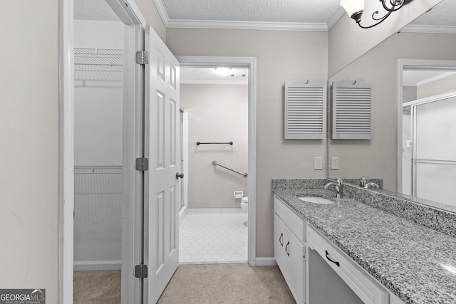 bathroom featuring a walk in closet, a textured ceiling, vanity, toilet, and ornamental molding