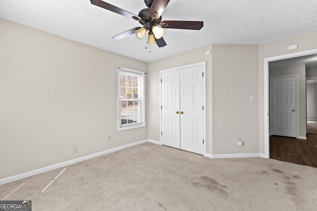 unfurnished bedroom with ceiling fan, light colored carpet, a textured ceiling, and a closet