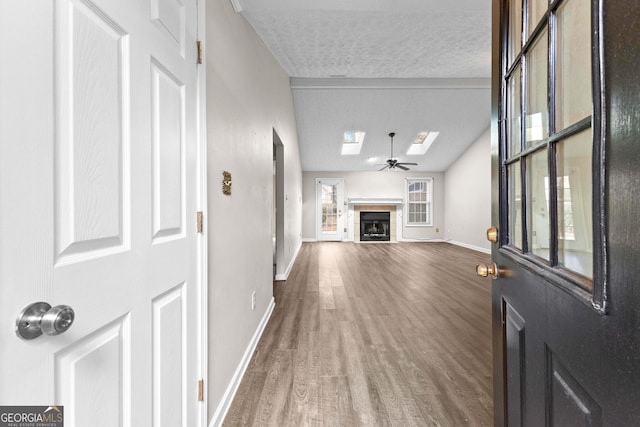 unfurnished living room with baseboards, a textured ceiling, wood finished floors, and a skylight
