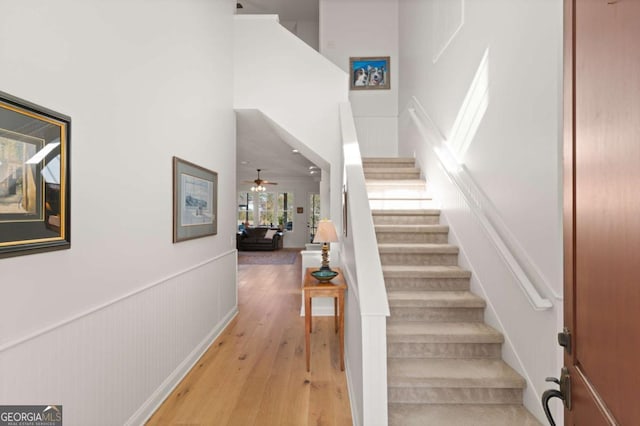 staircase featuring hardwood / wood-style flooring, a high ceiling, and ceiling fan