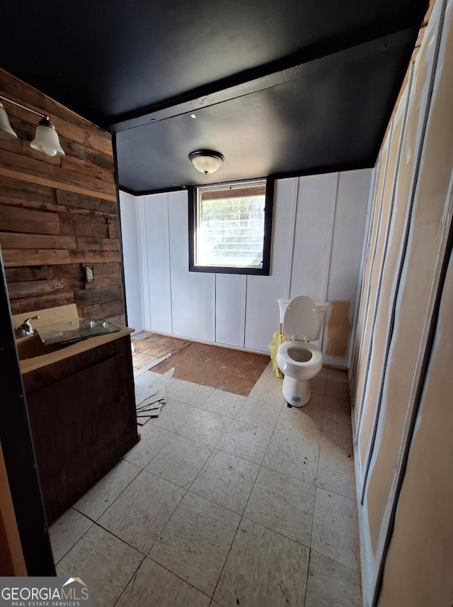 bathroom featuring vanity, toilet, and wood walls