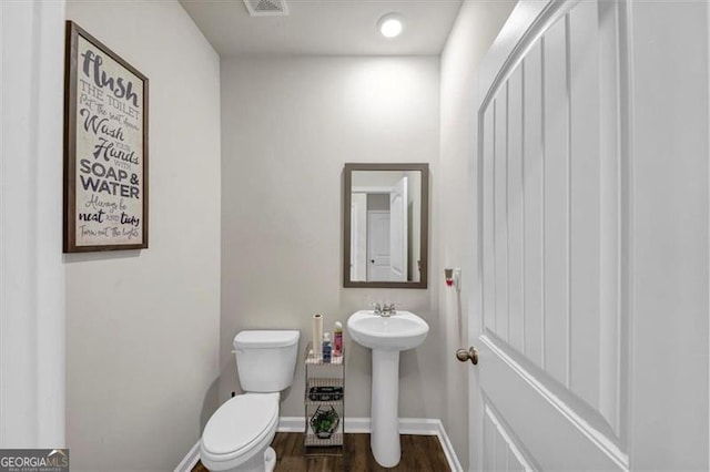 8819 Sibella Ct, Lithia Springs, GA 30122 - half bathroom with toilet, wood finished floors, baseboards, and a sink