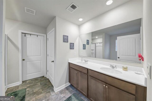 8819 Sibella Ct, Lithia Springs, GA 30122 - bathroom featuring baseboards, double vanity, stone finish floors, and recessed lighting