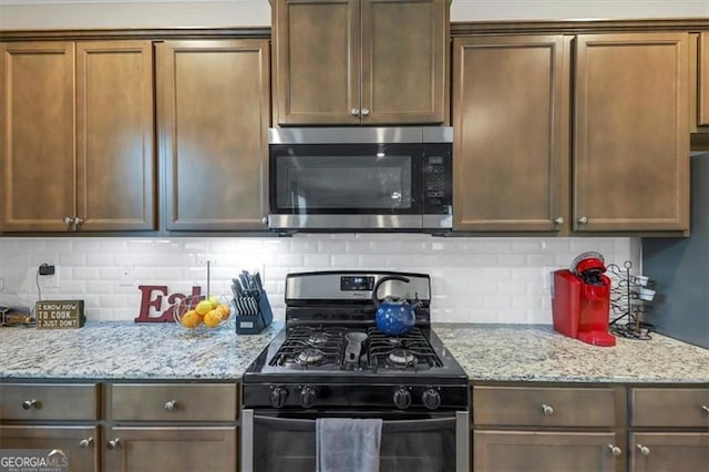 8819 Sibella Ct, Lithia Springs, GA 30122 - kitchen with stainless steel microwave, black range with gas stovetop, backsplash, and light stone countertops