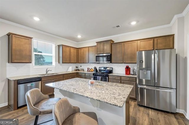 kitchen with sink, a center island, light stone counters, stainless steel appliances, and dark wood-type flooring