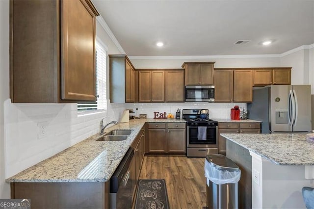 kitchen with appliances with stainless steel finishes, sink, backsplash, and light stone counters