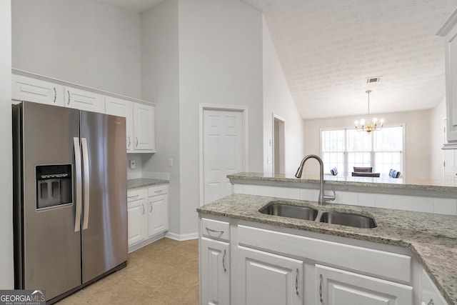 kitchen with stainless steel refrigerator with ice dispenser, sink, pendant lighting, light stone countertops, and white cabinets